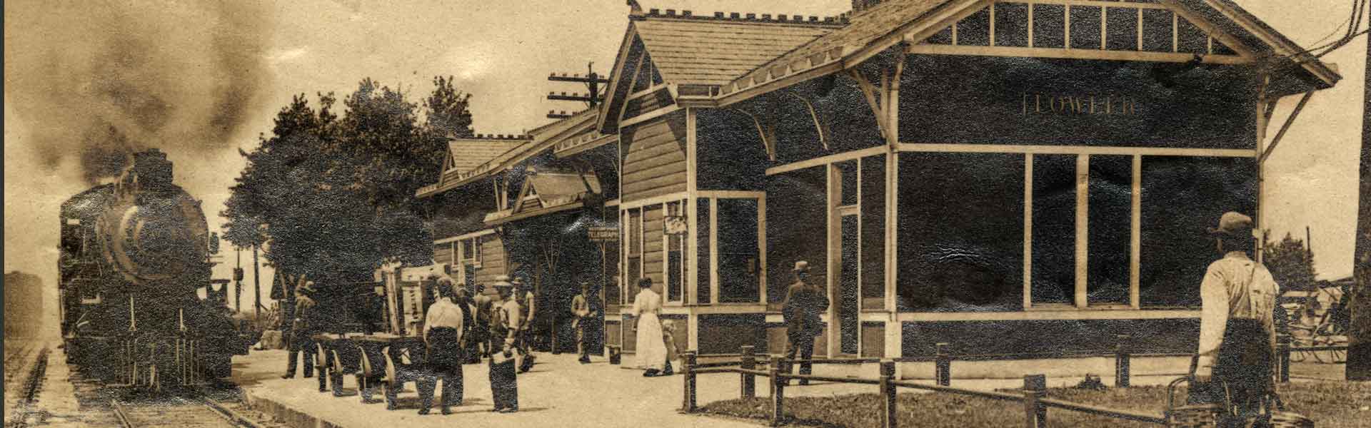 Railroad depot in Fowler, Indiana with train pulling into the station and people on the platform
